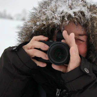 Fotografin in Wintermantel und Fotoapparat